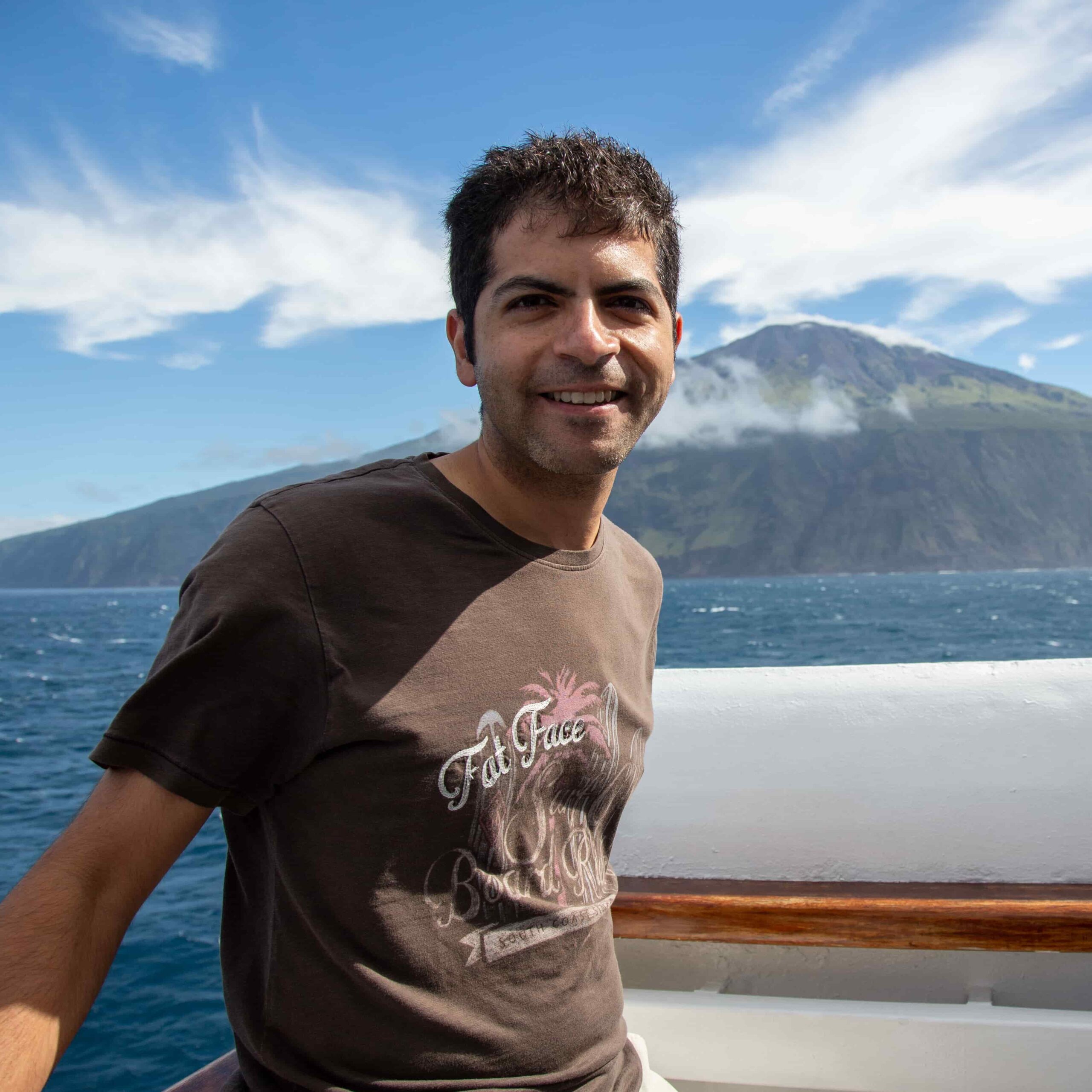 Aniket Sardana standing on a boat with an island in the background